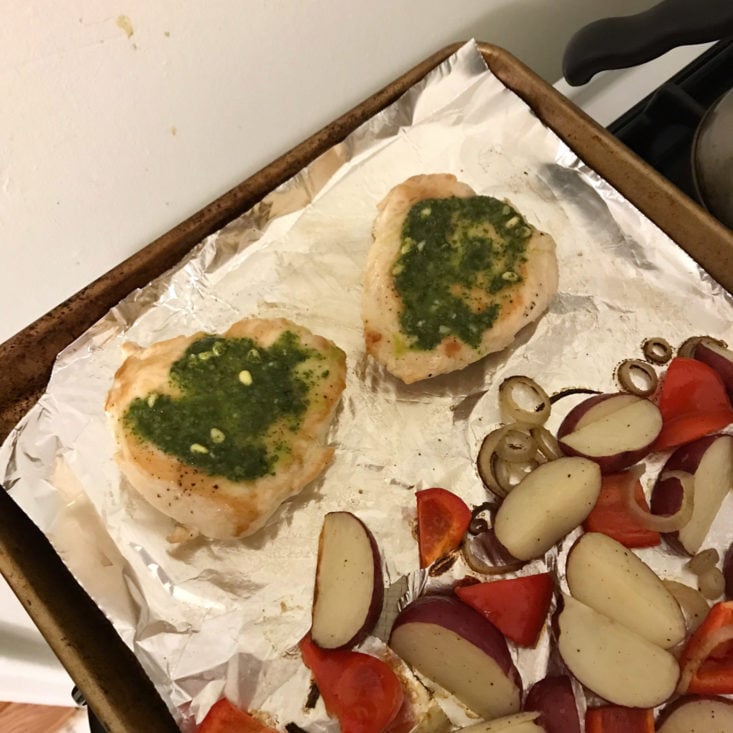 chicken topped with basil pesto on baking sheet