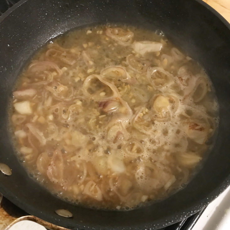 sliced shallots and garlic in pan with apple cider and chicken stock