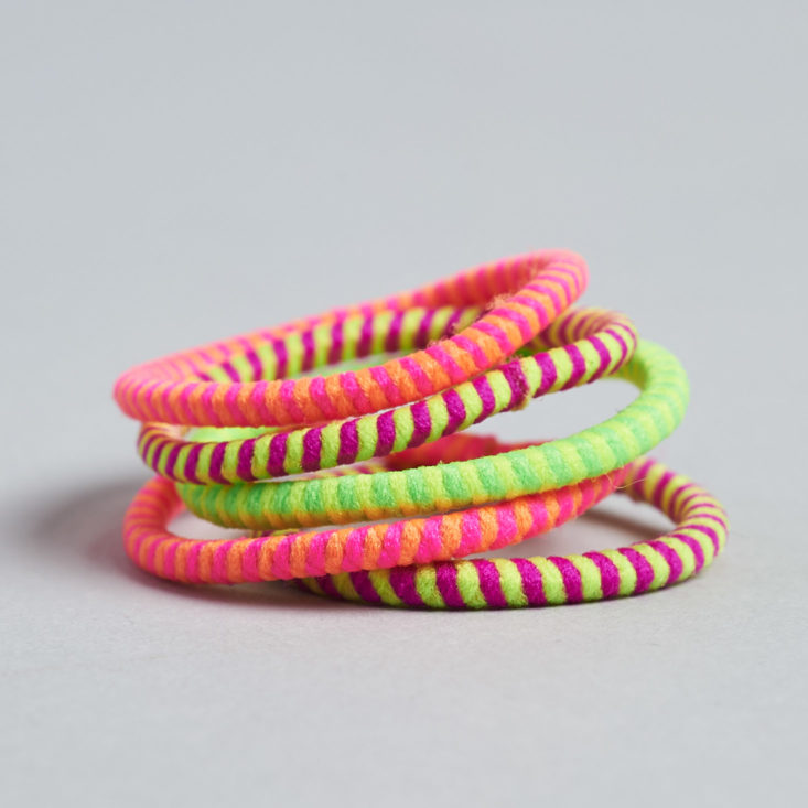 a stack of five small neon hair ties in pink and green