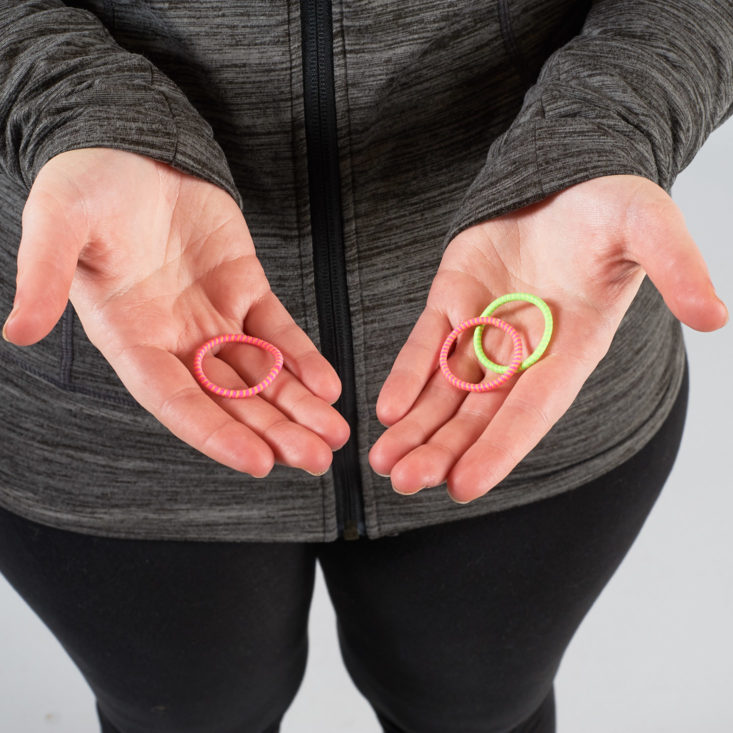 hands holding small neon hair ties