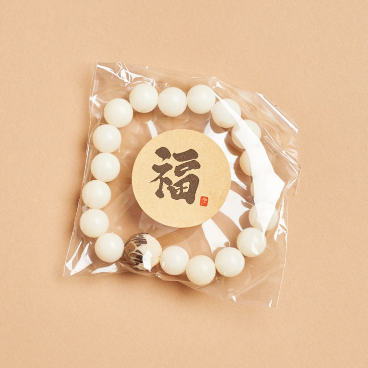 ivory beaded bracelet in a plastic package with chinese characters on it