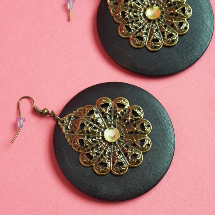 These earrings have a dangling stone-like disc and a smaller brass accent.