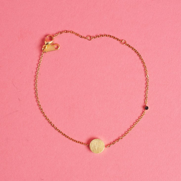 This bracelet features a simple gold charm and a tiny gem