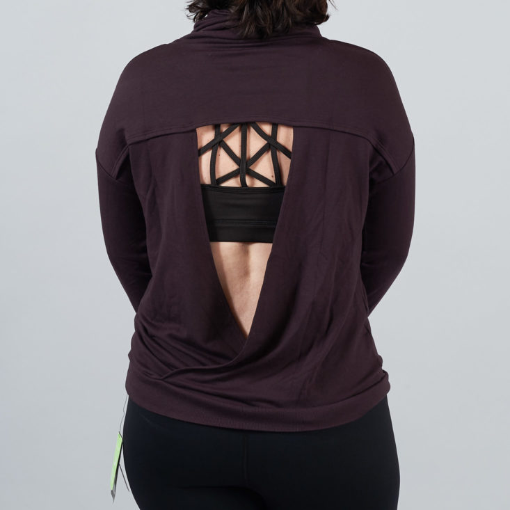 triangular opening in the back of a burgundy pullover on a woman