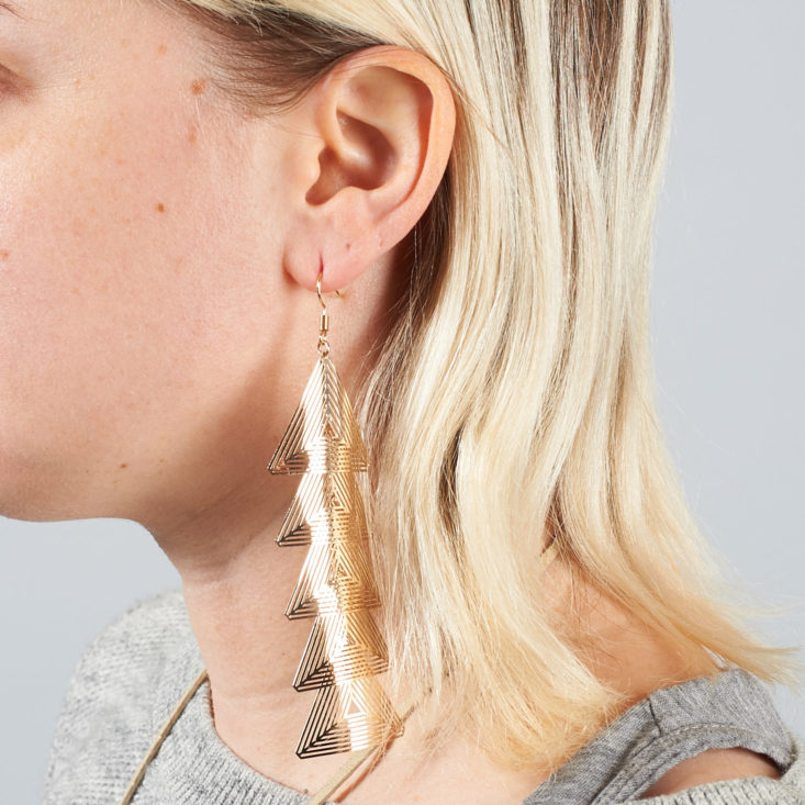 Gold dangly triangle earrings on model