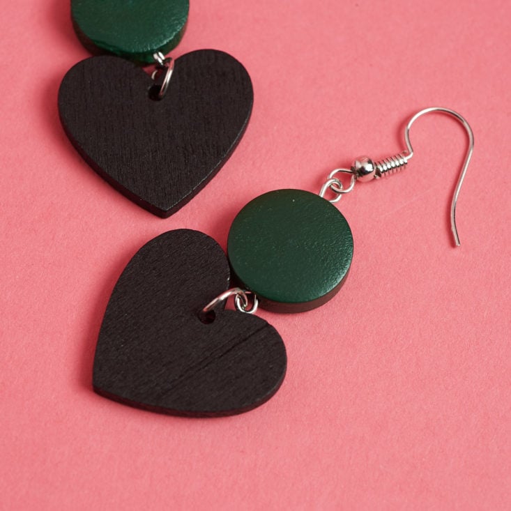 closeup on black heart earrings with green discs