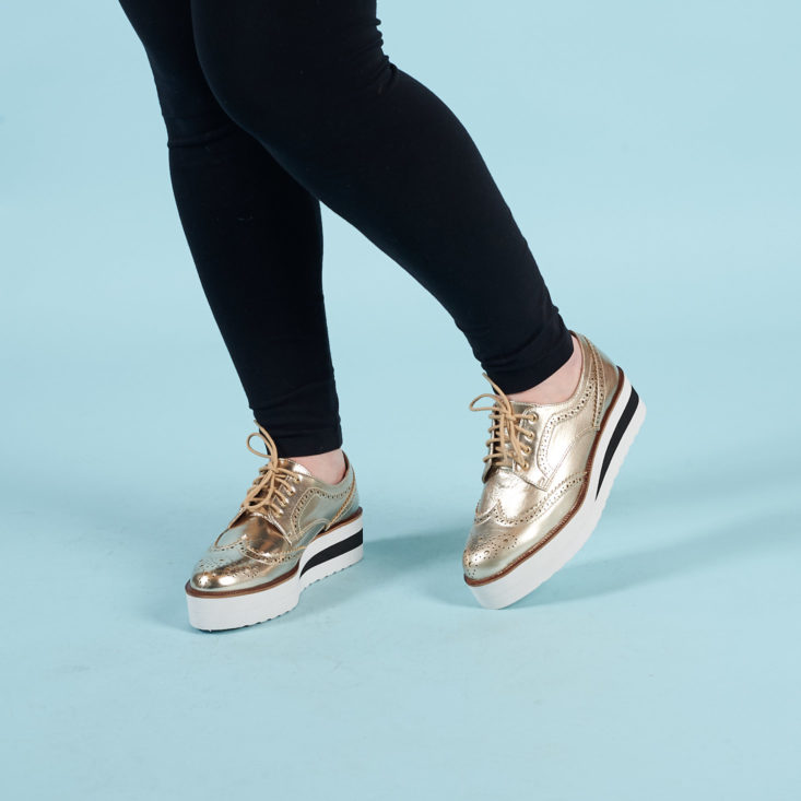 gold brogue shoes with white platforms on model