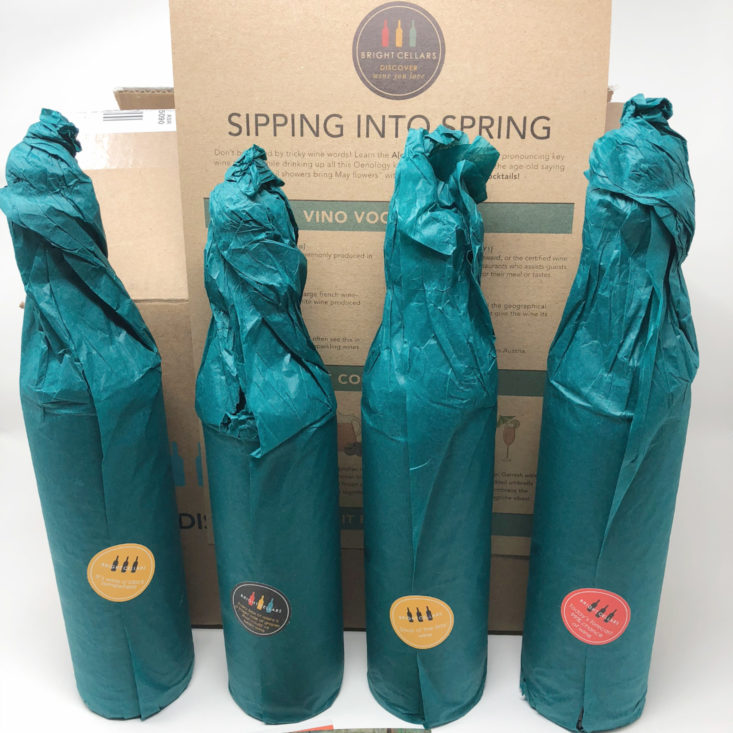 four bottles of wine wrapped in teal paper