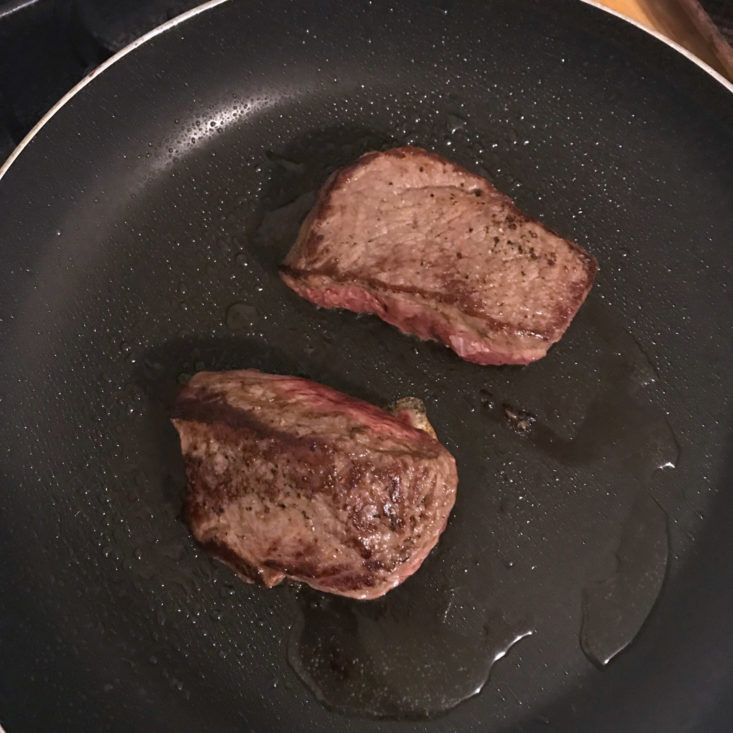 steaks cooking in pan