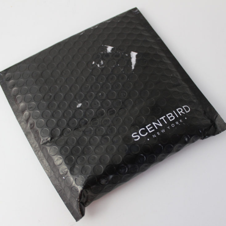 black bubble mailer with Scentbird printed in white laying on a white background