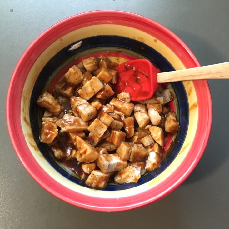 diced chicken for the korean BBQ chicken sandwich mixed with BBQ sauce in a striped bowl