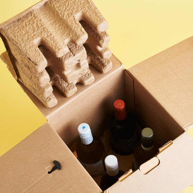 top-down view of the interior of the open box with a molded shipping insert off to the top left, and the tops of all four bottles visible