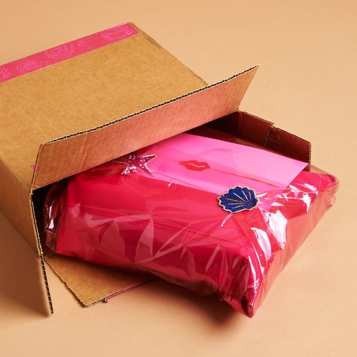 Pink wrapped package spilling out of cardboard box